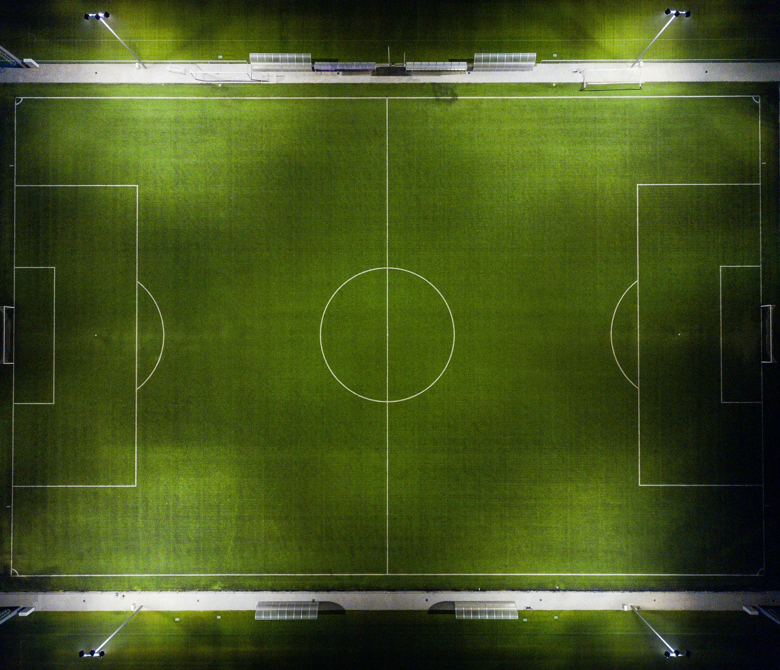 Aerial view of a floodlit football pitch at night